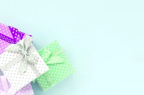 Pile of a small colored gift boxes with ribbons lies on a violet background Stock Photos