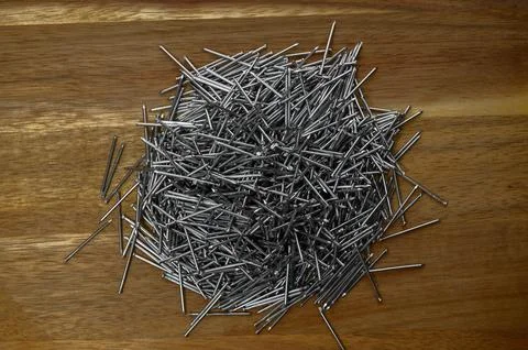 A pile of small nails on a wooden table Stock Photos