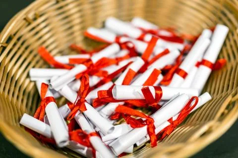 Pile of small paper scrolls in wicked basket.  White scrolls tied with red ri Stock Photos