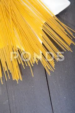 Pile of spelt spaghetti on white platen on wooden table Stock Photos