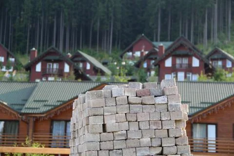 Pile Of Square Construction Bricks In Front Of Wooden Houses Stock Photos