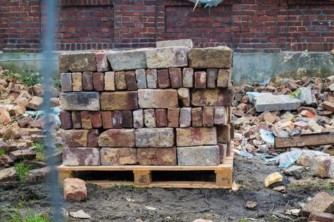 Pile of stacked bricks against the background of a demolished building Stockfoto's