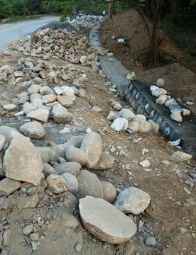 A pile of stone alongside road for constructing a stone retaining wall to pre 스톡 사진