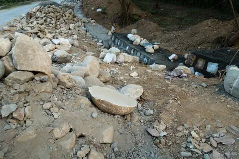 A pile of stone alongside road for constructing a stone retaining wall to pre 스톡 사진