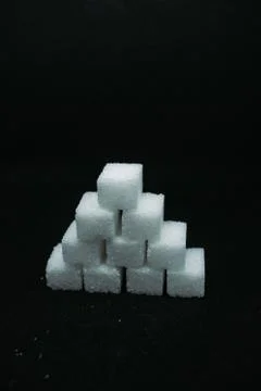 Pile of sugar cubes closeup view on black dark isolated background Stock Photos