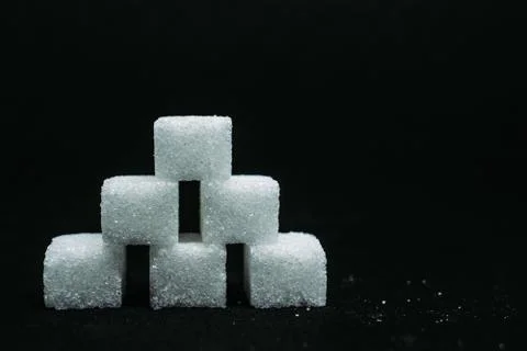 Pile of sugar cubes closeup view on black dark isolated background Stock Photos
