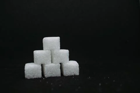 Pile of sugar cubes closeup view on black dark isolated background Foto stock