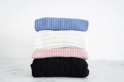 Pile of sweaters and knits in different color fabric neatly folded and piled  Stock Photos