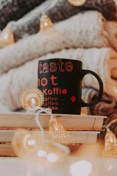 A pile of sweaters, a stack of old books, a beautiful black and red cup, ligh Foto stock