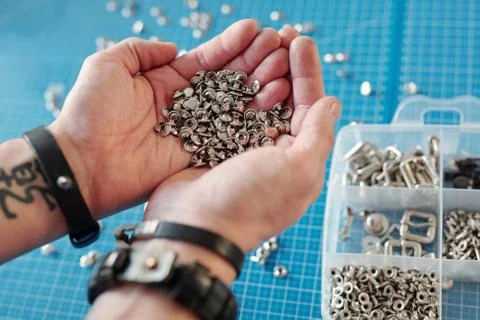 Pile of tiny metallic knobs in hands of young creative craftsman Foto stock