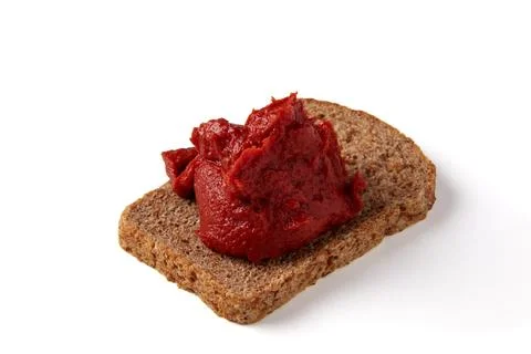 Pile of tomato paste on a piece of rye bread isolated on white background. Foto stock
