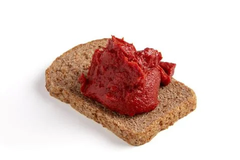 Pile of tomato paste on a piece of rye bread isolated on white background. Stock Photos