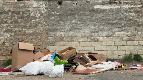 Pile of Trash and Construction Debris Sits Abandoned Against an Old Stone Wall Stock Footage 333185495