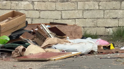 Pile of Trash and Construction Debris Sits Abandoned Against an Old Stone Wall Stock Footage 333185531