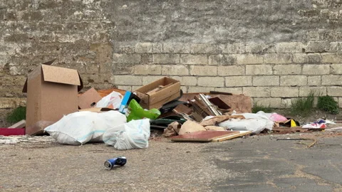 Pile of Trash and Construction Debris Sits Abandoned Against an Old Stone Wall Stock Footage 333299940