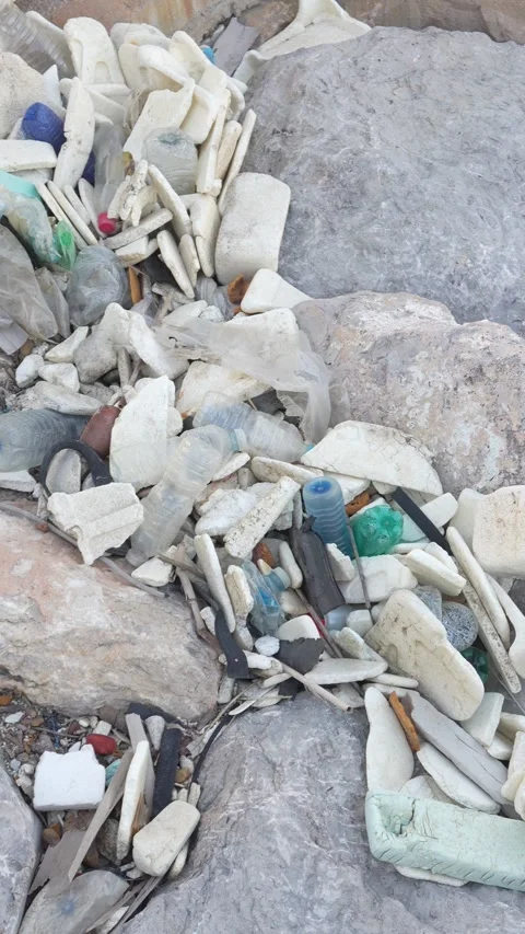A pile of trash is on the ground, including plastic bottles and rocks Stock Footage 276343950