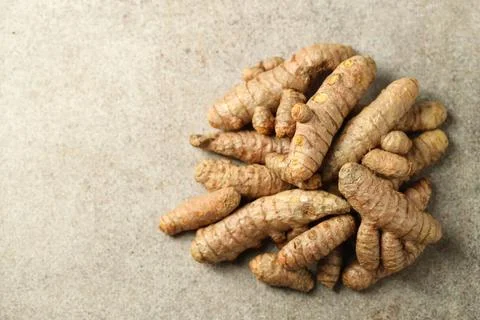 Pile of tumeric rhizomes on grey table, top view. Space for text Stock Photos