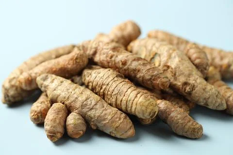 Pile of tumeric rhizomes on light blue background, closeup Stock Photos