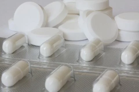 Pile of two different kind of white pills - some in plastic blister package Stock Photos