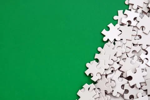 A pile of uncombed elements of a white jigsaw puzzle lies on the background o Stock Photos