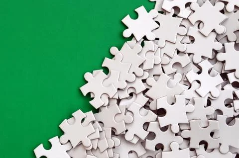 A pile of uncombed elements of a white jigsaw puzzle lies on the background o 스톡 사진