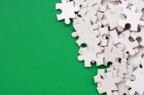 A pile of uncombed elements of a white jigsaw puzzle lies on the background o Stock Photos