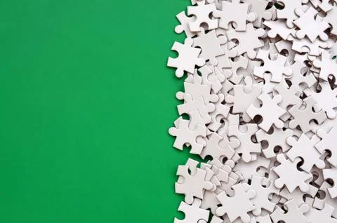 A pile of uncombed elements of a white jigsaw puzzle lies on the background o 스톡 사진