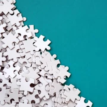 A pile of uncombed elements of a white jigsaw puzzle lies on the background o 스톡 사진