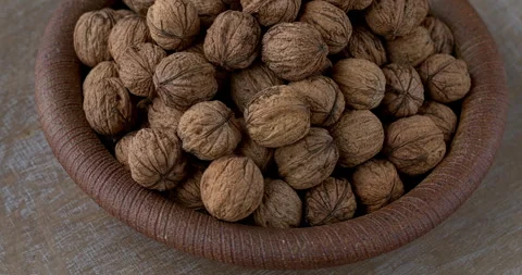 Pile of walnut nuts in ceramic handmade bowl. Table spin. Video stock 279174495