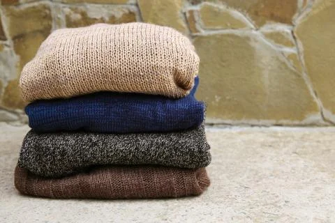 Pile of warm clothes on stone background. Stock Photos