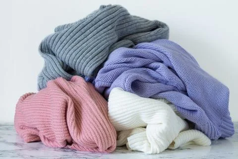 Pile of warm sweaters on marble table. Autumn and winter clothes for donation Stock Photos