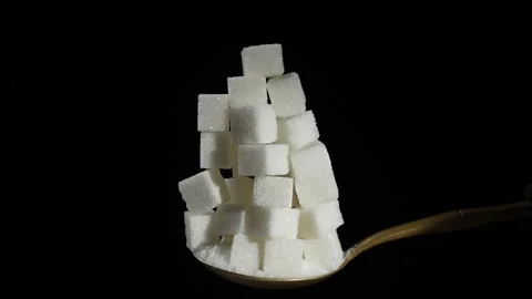 Pile of white cubes sugar on spoon falling on black background, slow motion Stock Footage 306820363