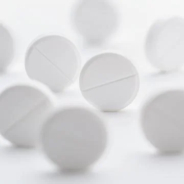A pile of white pills scattered on a bright white background. Selective focus Stock Photos