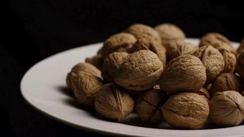 Pile of whole walnuts rotating on a white plate Stock Footage 328144074