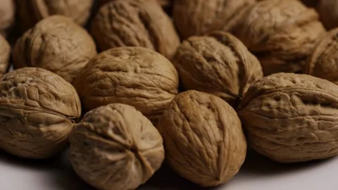 Pile of whole walnuts in shells rotating on white Stock Footage 328136100