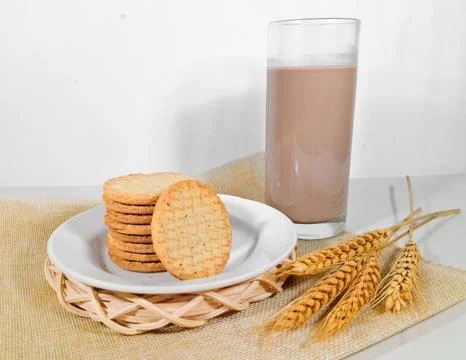 A pile of whole wheat biscuits or healthy crackers on a plate with a glass Stock Photos