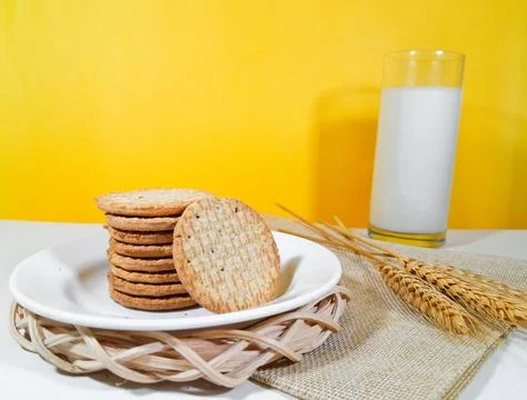 A pile of whole wheat biscuits or healthy crackers on a plate with a glass Stock Photos