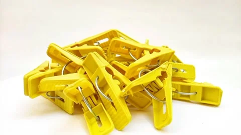 A pile of yellow laundry clips rotating on the white background, plastic clips Stock Footage 306038736