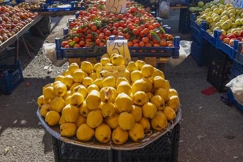 A pile of yellow lemons sits on a table in front of a fruit stand Stock-Fotos