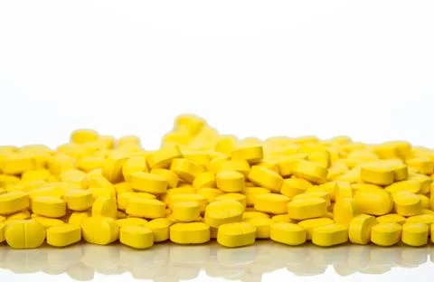 Pile of yellow ovoid-rectangular shape tablet pills isolated on white backgro Foto stock