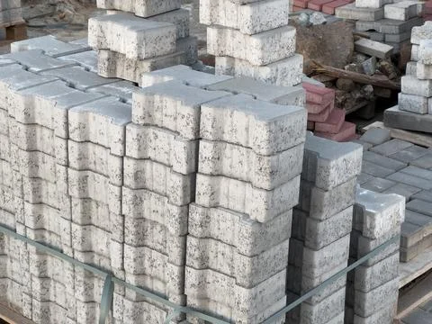 Piled concrete blocks and patterned stones are organized neatly at a busy c.. Фото