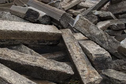 Piled up, lying in disarray old rectangular cement grey road curbs. Stock Photos