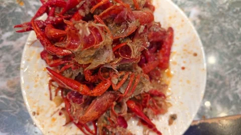 Piled Red Cooked Crawfish Shells on Messy White Plate Over Marble Tabletop Vídeos de archivo 339351466