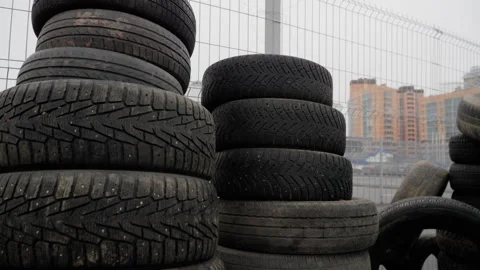 Piled rubber tires lean against rusty chain-link fence Stock Footage 314639481
