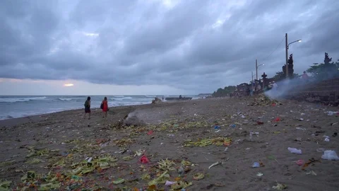 PIles of burning offerings on a littered beach in Bali Video stock 74289843