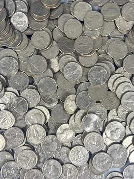 Piles of coins spread across a flat surface in a storage area Stock Photos