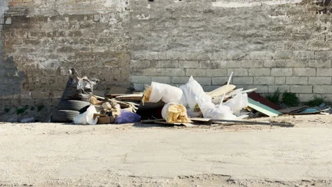 Piles of Construction Waste and Trash Clutter Alleyway Beside Old Stone Wall Stock-Footage 333561983