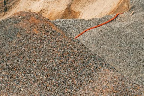 Piles of crushed stone aggregate and a laid orange utility pipe at a buildi.. Fotos Stock