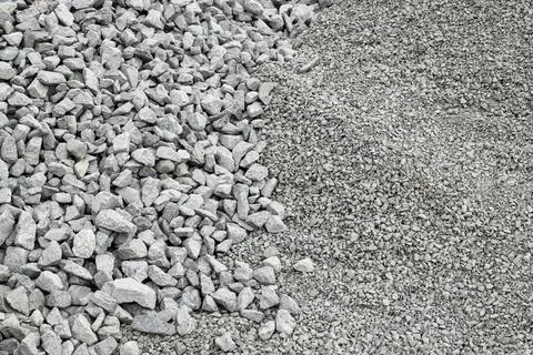 Piles of gray aggregate stone materials at a construction site in daylight Photos