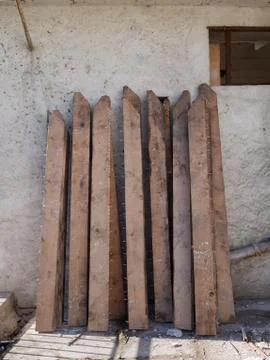 Piles of old planks with rusty nails propped against the wall. Stockfoto's